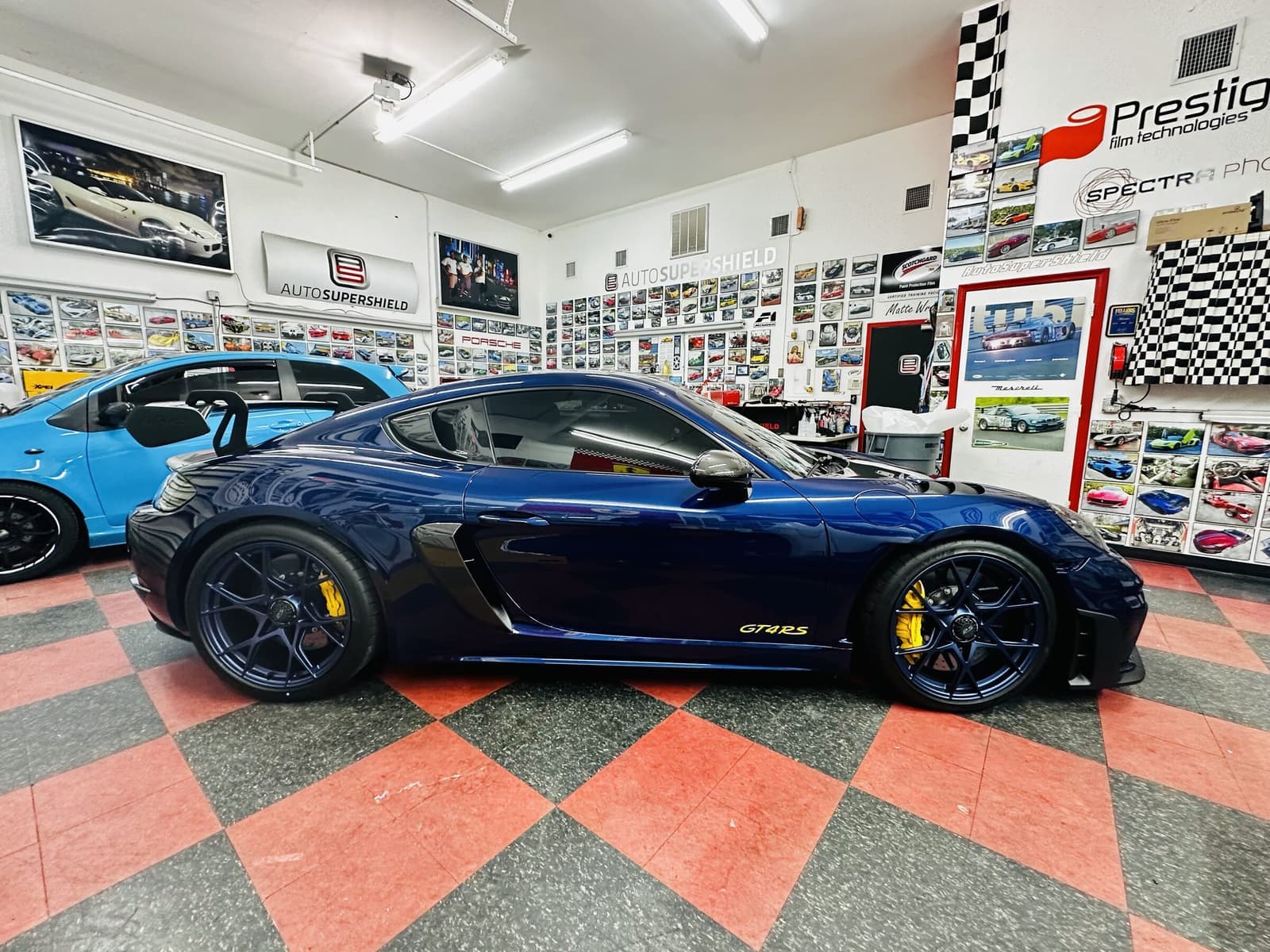 Inside Auto SuperShield's Boca Raton studio — checker floor, cars in the bays